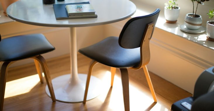 round white dining table beside two chairs on brown hardwood flooring