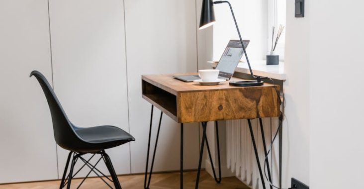 Bright minimalist home office with modern wooden desk, chair, and natural light.